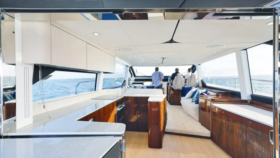 Modern yacht interior featuring a spacious kitchen area and seating, with three men gazing out at the ocean view.